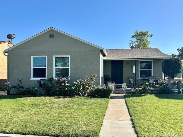 view of front of home featuring a porch, a front lawn, roof with shingles, and stucco siding
