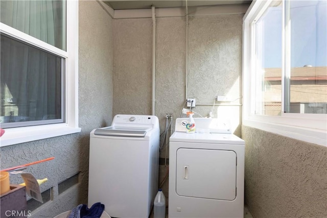 laundry area with separate washer and dryer, a textured wall, and laundry area