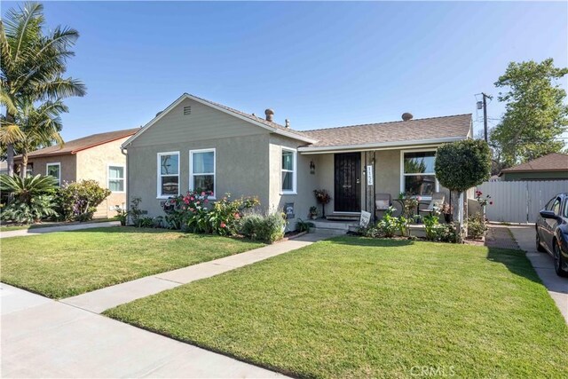 ranch-style home featuring stucco siding, a front lawn, and fence