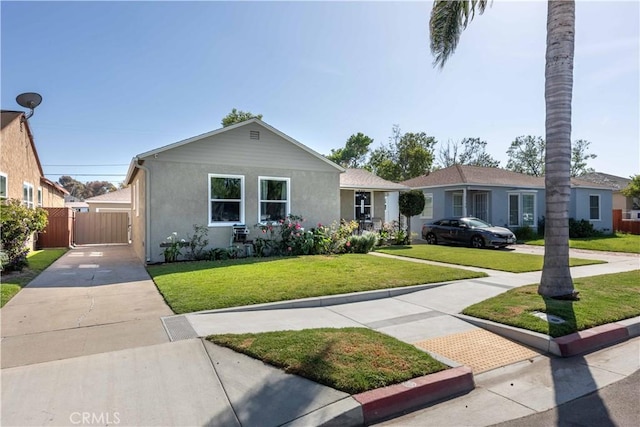 view of front of property with fence, a front lawn, driveway, and stucco siding