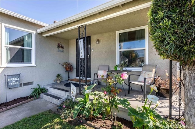doorway to property with covered porch and stucco siding