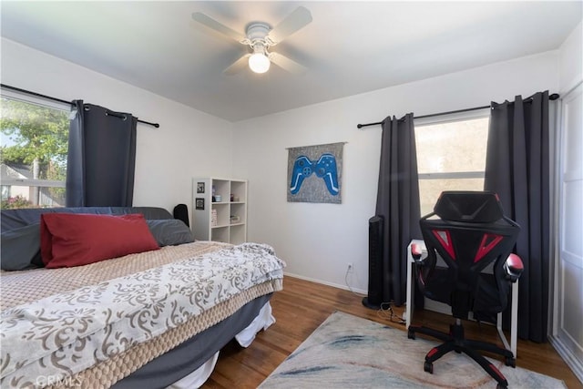 bedroom featuring wood finished floors, a ceiling fan, and baseboards