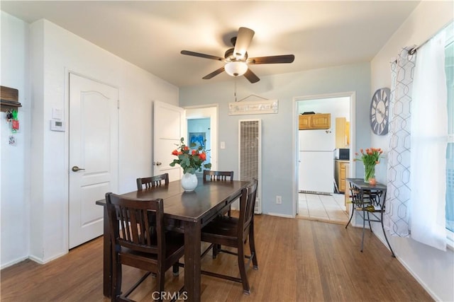 dining room with ceiling fan, baseboards, a heating unit, and light wood finished floors