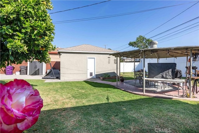 view of yard with an outdoor structure, a patio, and fence