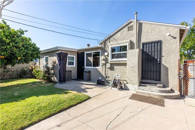 rear view of property with a yard, a patio, stucco siding, and fence