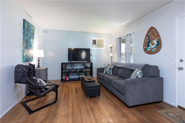 living area featuring baseboards, wood finished floors, and a wall mounted air conditioner