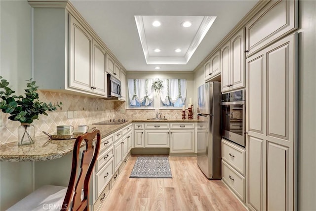 kitchen with decorative backsplash, light stone countertops, light wood-type flooring, a sink, and stainless steel appliances