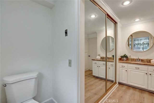 bathroom with crown molding, wood finished floors, vanity, toilet, and recessed lighting