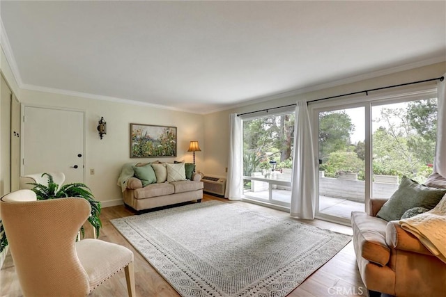 living room with crown molding, baseboards, and light wood-style flooring