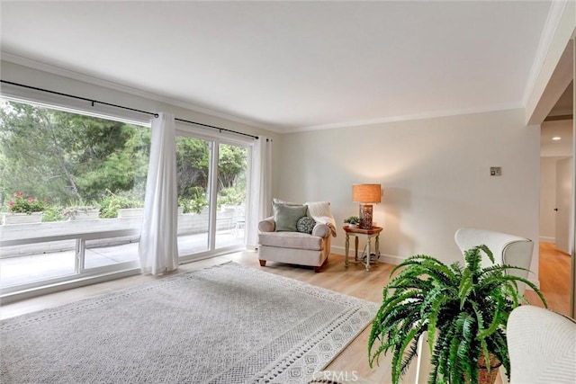 living area featuring crown molding, baseboards, and light wood-style flooring