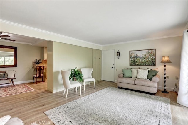 living area with crown molding, baseboards, ceiling fan, and light wood-style floors