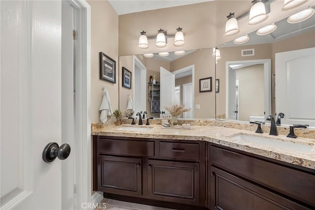bathroom featuring visible vents, a sink, and double vanity