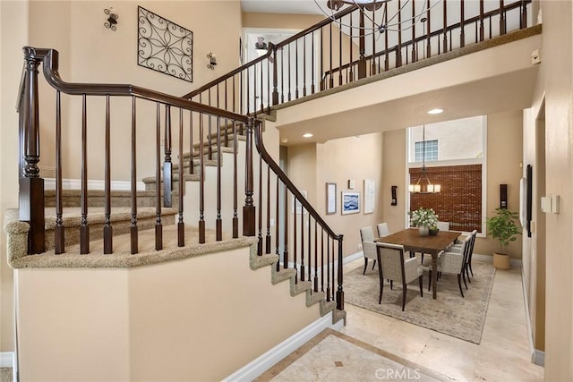 stairway featuring recessed lighting, a towering ceiling, baseboards, and an inviting chandelier