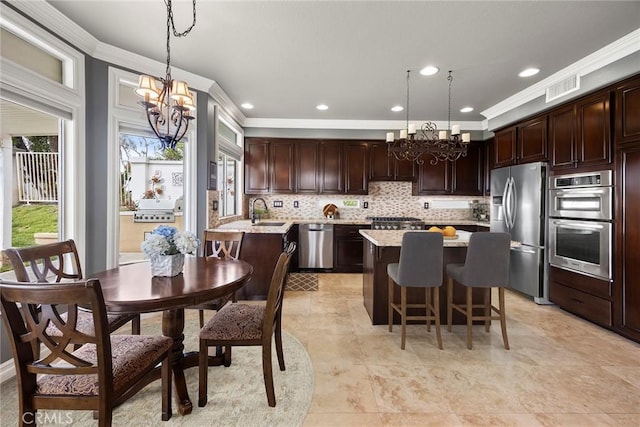 kitchen with appliances with stainless steel finishes, ornamental molding, visible vents, and a notable chandelier