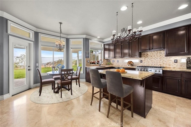 kitchen with ornamental molding, a center island, dark brown cabinetry, decorative backsplash, and a notable chandelier