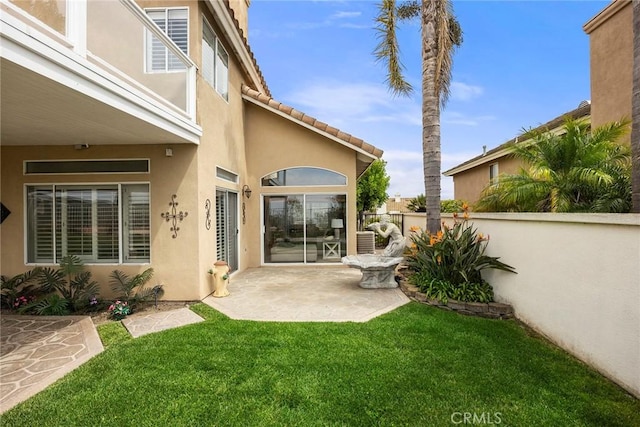 back of property with a patio area, a lawn, stucco siding, and fence