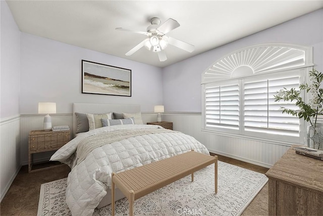carpeted bedroom featuring wainscoting and ceiling fan