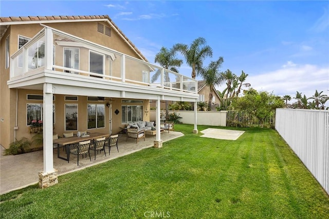 rear view of property with a fenced backyard, a yard, stucco siding, a patio area, and an outdoor living space