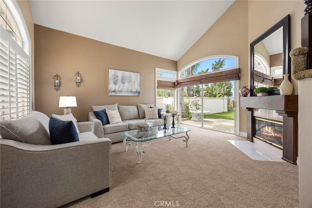 carpeted living area featuring high vaulted ceiling and a fireplace with flush hearth