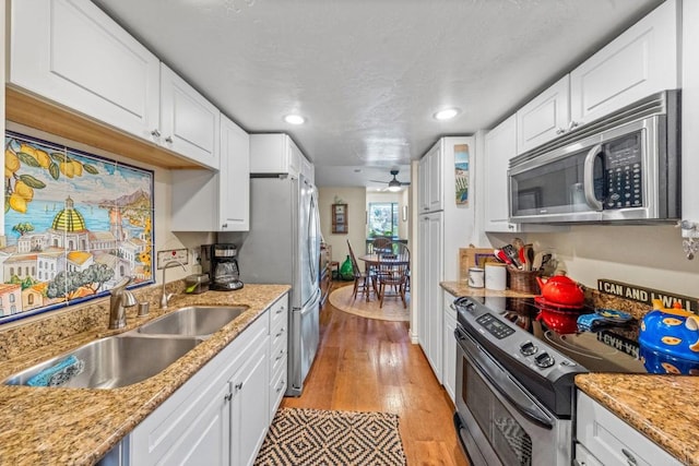 2564 Navarra Dr Unit 113, Carlsbad, CA 92009 - kitchen featuring appliances with stainless steel finishes, a sink, white cabinetry, ceiling fan, and light wood-style flooring