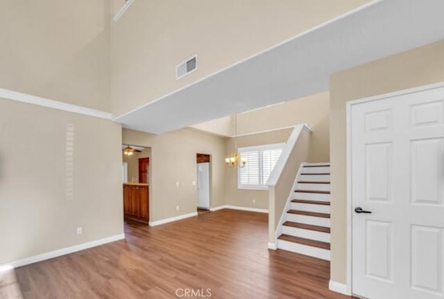 49 El Cencerro, Rancho Santa Margarita, CA 92688 - unfurnished living room with visible vents, stairs, a towering ceiling, wood finished floors, and a chandelier