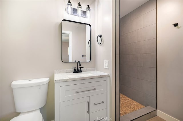 bathroom with tiled shower, vanity, and toilet