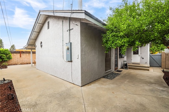 exterior space featuring fence, a patio area, a gate, and stucco siding