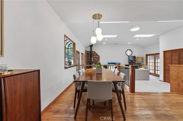 dining area with vaulted ceiling with skylight, light wood-style floors, and baseboards