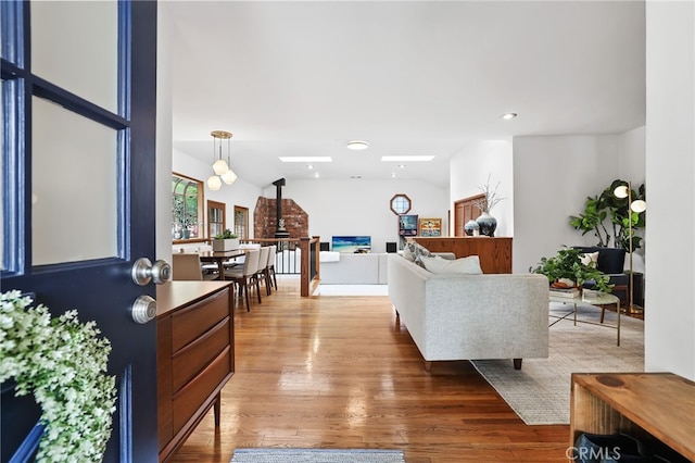 living room with vaulted ceiling, a wood stove, wood finished floors, and recessed lighting