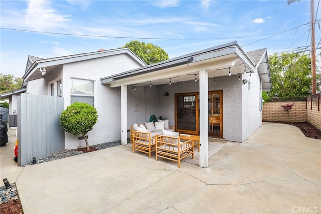 rear view of house with fence, a patio, stucco siding, and an outdoor living space