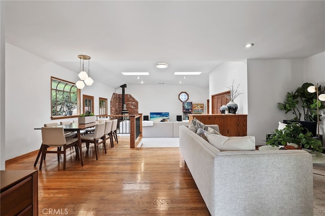 living room with vaulted ceiling, baseboards, recessed lighting, wood finished floors, and a wood stove