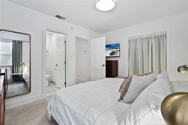 bedroom with connected bathroom, carpet flooring, and visible vents