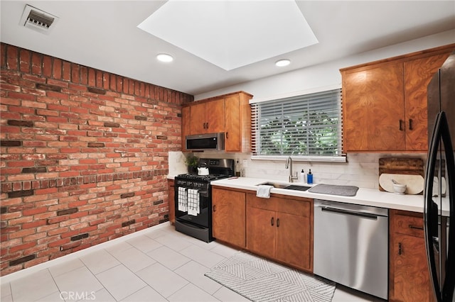 kitchen featuring visible vents, a skylight, brick wall, light countertops, and appliances with stainless steel finishes