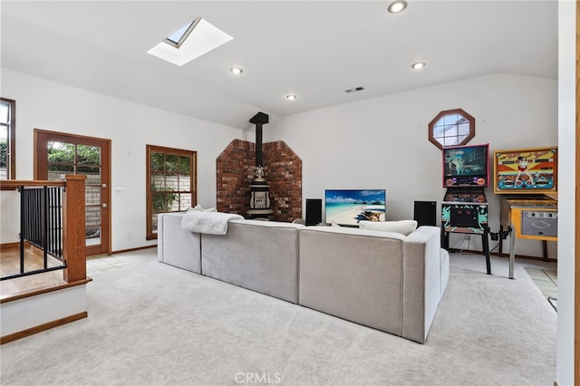 living area with lofted ceiling with skylight, a wood stove, carpet, visible vents, and recessed lighting