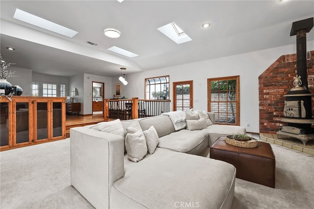 living room with carpet, a wood stove, a skylight, and a healthy amount of sunlight