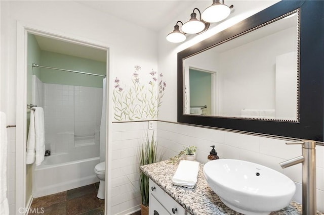 bathroom with toilet, shower / bath combo with shower curtain, stone finish floor, and vanity