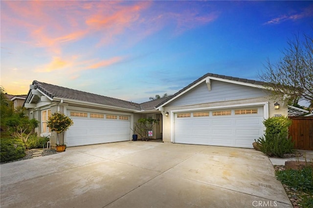 single story home featuring a tile roof, a garage, fence, concrete driveway, and stucco siding
