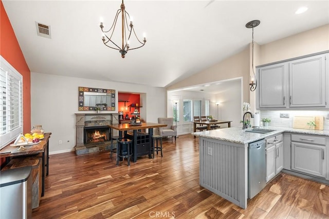 kitchen featuring a peninsula, lofted ceiling, gray cabinets, a sink, and dishwasher