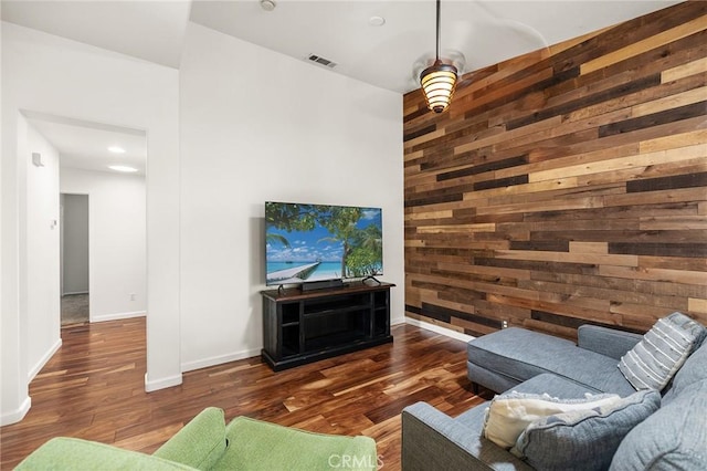 living room with baseboards, wood walls, wood finished floors, and visible vents