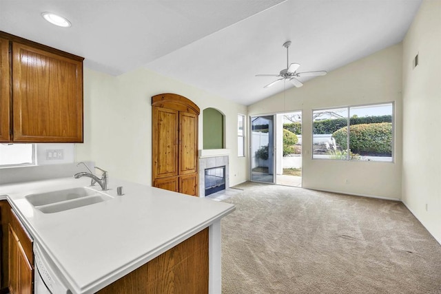 6017 Piros Way, Oceanside, CA 92056 - kitchen with light colored carpet, a tiled fireplace, vaulted ceiling, a sink, and light countertops