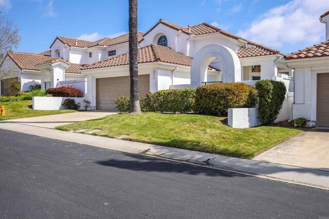 6017 Piros Way, Oceanside, CA 92056 - mediterranean / spanish-style house with driveway, a tile roof, a front lawn, an attached garage, and stucco siding
