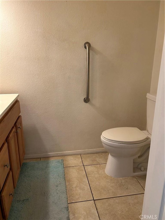 half bath featuring tile patterned flooring, baseboards, toilet, and vanity