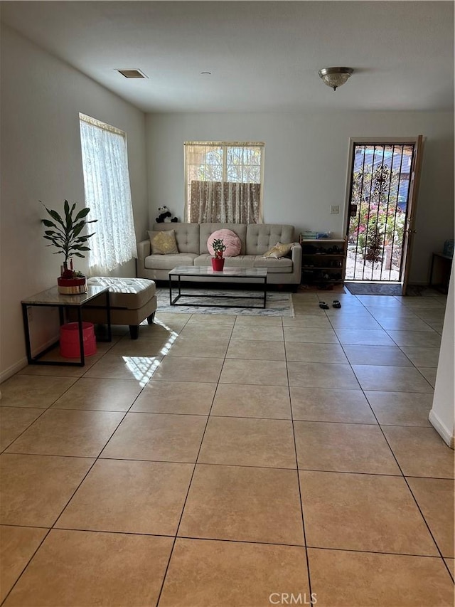 living area with a wealth of natural light, tile patterned floors, visible vents, and baseboards