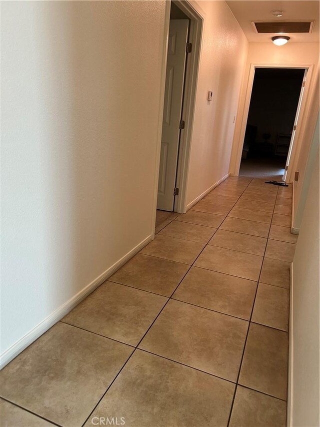 hall with baseboards and light tile patterned floors
