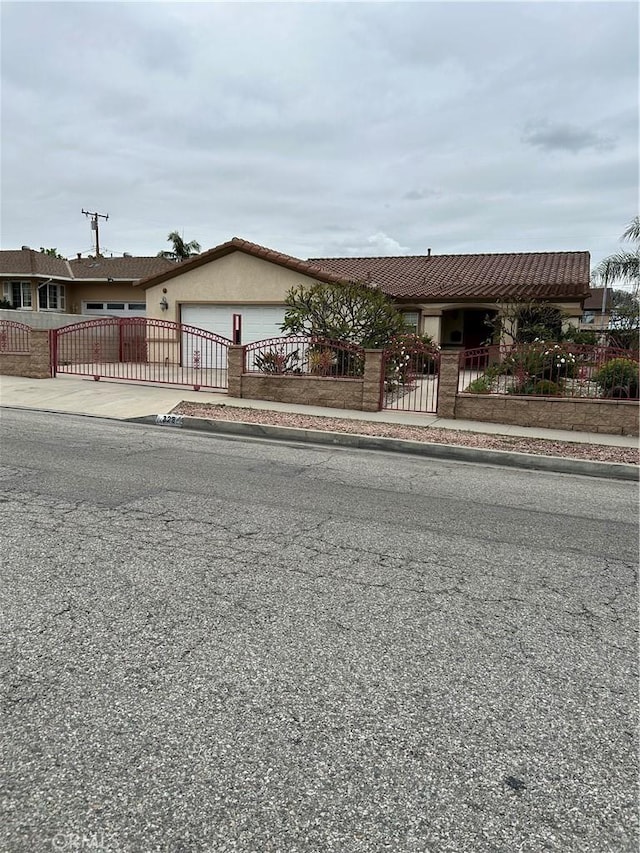 single story home featuring a gate, an attached garage, concrete driveway, and a fenced front yard