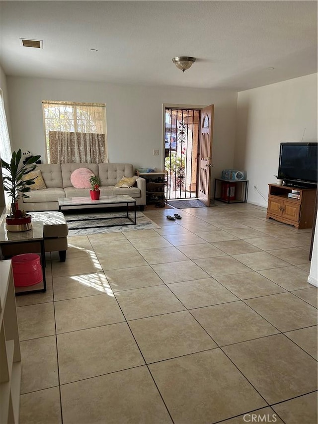 living room featuring light tile patterned flooring, plenty of natural light, and visible vents
