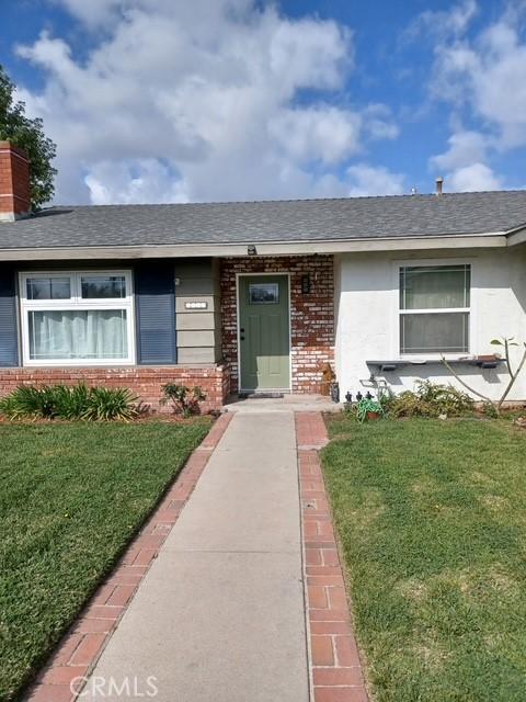 single story home with roof with shingles, a front lawn, and brick siding