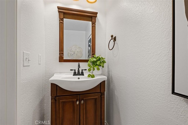 bathroom with a textured wall and vanity