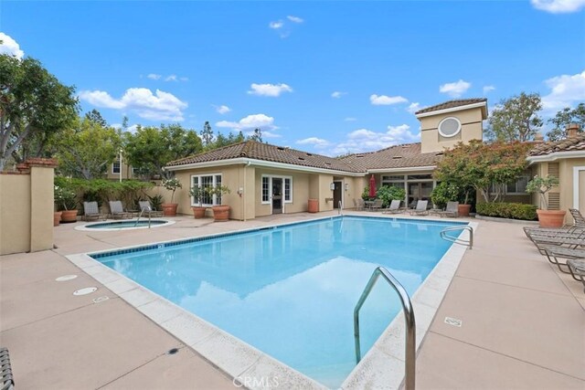 community pool with a patio area and a community hot tub