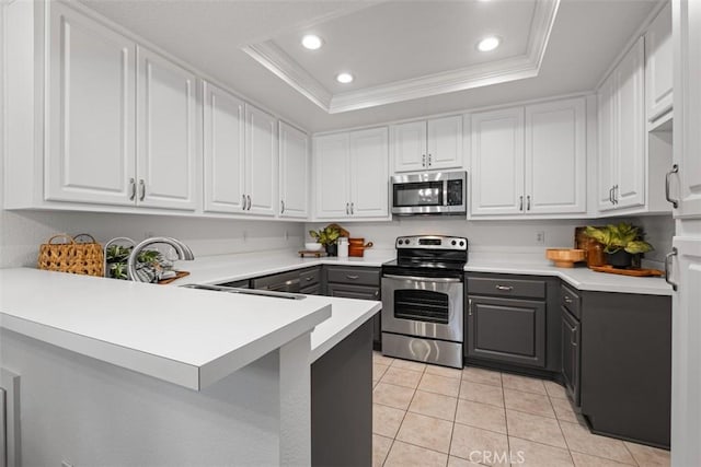 kitchen featuring appliances with stainless steel finishes, a raised ceiling, gray cabinetry, light tile patterned flooring, and recessed lighting